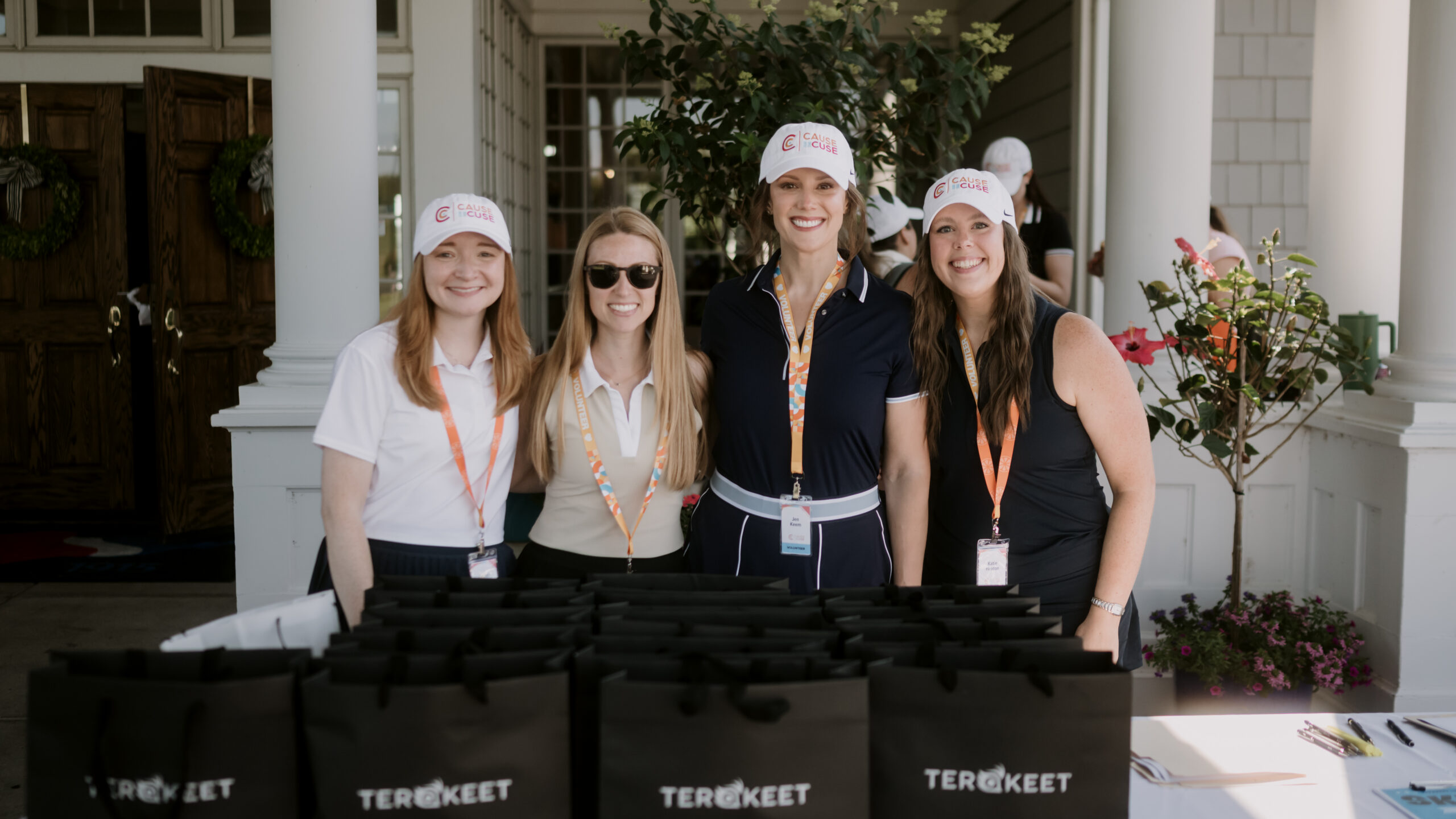 Four women in volunteer hats stand behind Terakeet gift bags